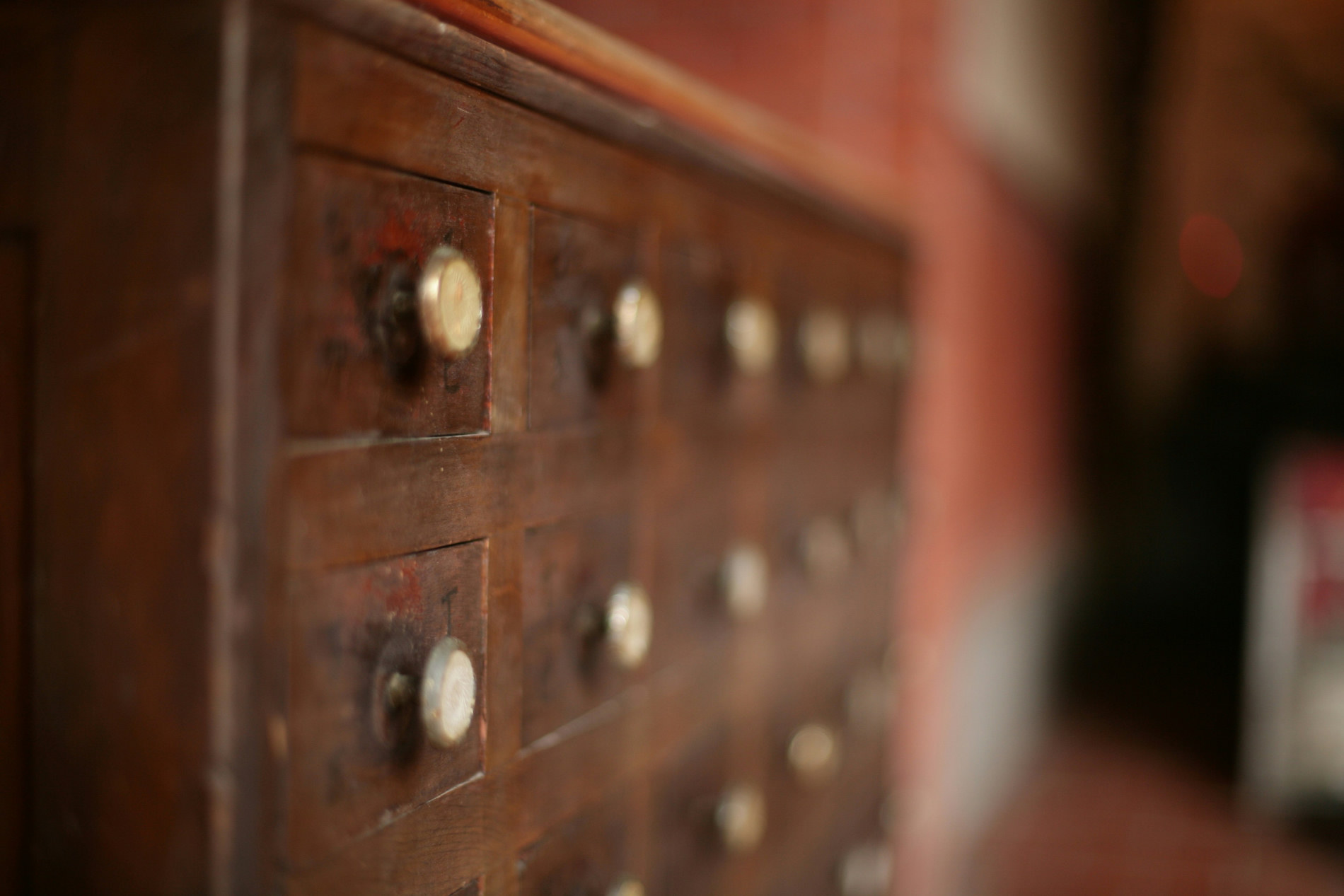 Close view of a wooden cabinet with rows of small drawers and brass knobs