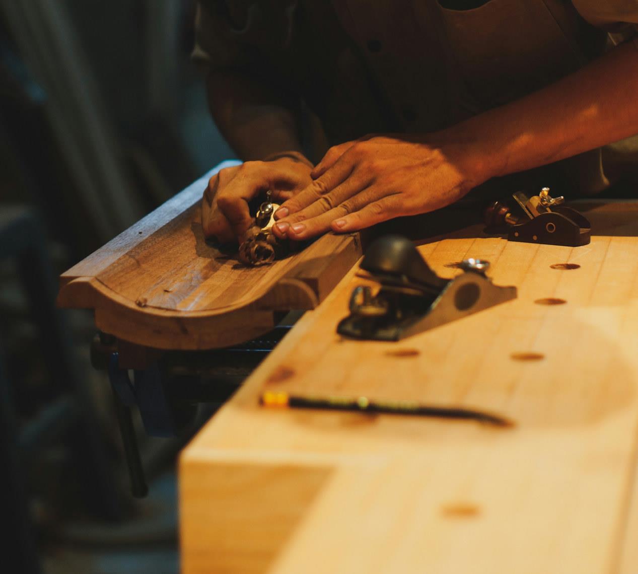 Hands planing timber at the bench